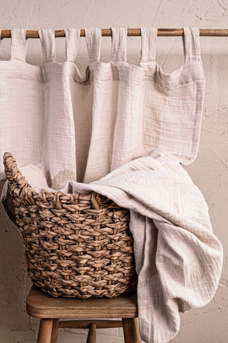 Cream tab top panel with basket on stool. Handwoven 2-layer muslin cotton curtain, Denizli, OEKO-TEX. Vivamaison.