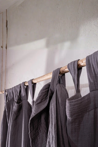 Gray tab loops on rustic rod closeup. Handwoven 2-layer muslin cotton curtain, Denizli, OEKO-TEX. Vivamaison.