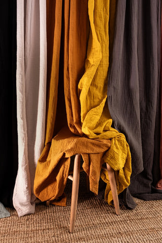 Rust yellow gray drapes styled over stool. Handwoven 2-layer muslin cotton curtain, Denizli, OEKO-TEX. Vivamaison.