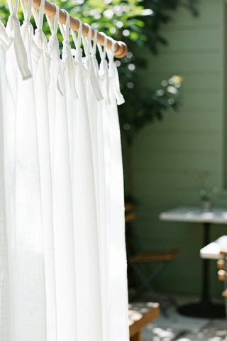 White tie knots closeup on wooden rod, patio. Handwoven 2-layer muslin cotton curtain, Denizli, OEKO-TEX. Vivamaison.