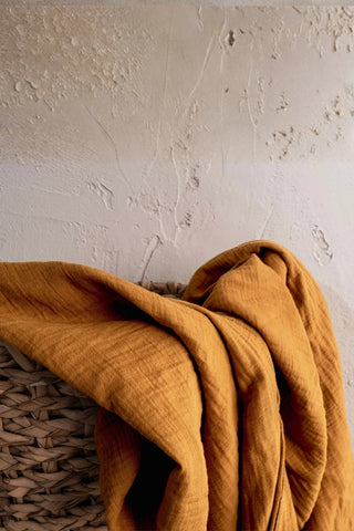 Mustard fabric folds closeup over basket. Handwoven 2-layer muslin cotton curtain, Denizli, OEKO-TEX. Vivamaison.