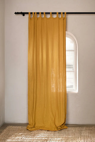 Mustard tab top panel beside arched window. Handwoven 2-layer muslin cotton curtain, Denizli, OEKO-TEX. Vivamaison.