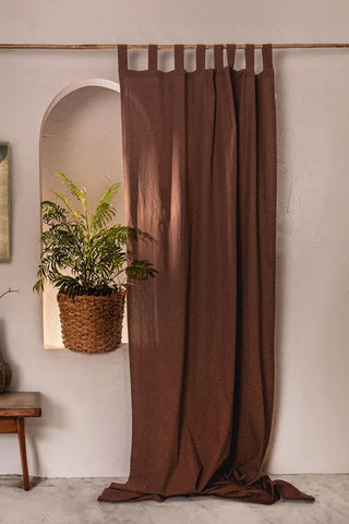 Brown stonewashed cotton curtain panel, tab top, beside a plant niche. Handwoven in Denizli, OEKO-TEX. Vivamaison.