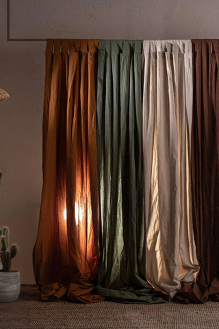 Four stonewashed cotton curtain panels glowing with warm backlight. Handwoven in Denizli, OEKO-TEX. Vivamaison.