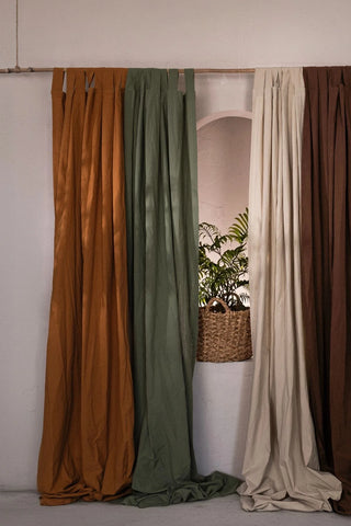 Four stonewashed cotton curtain colors on a bamboo rod beside a niche plant. Handwoven in Denizli, OEKO-TEX. Vivamaison.
